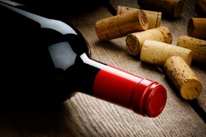 Bottle of red wine and corks on wooden table